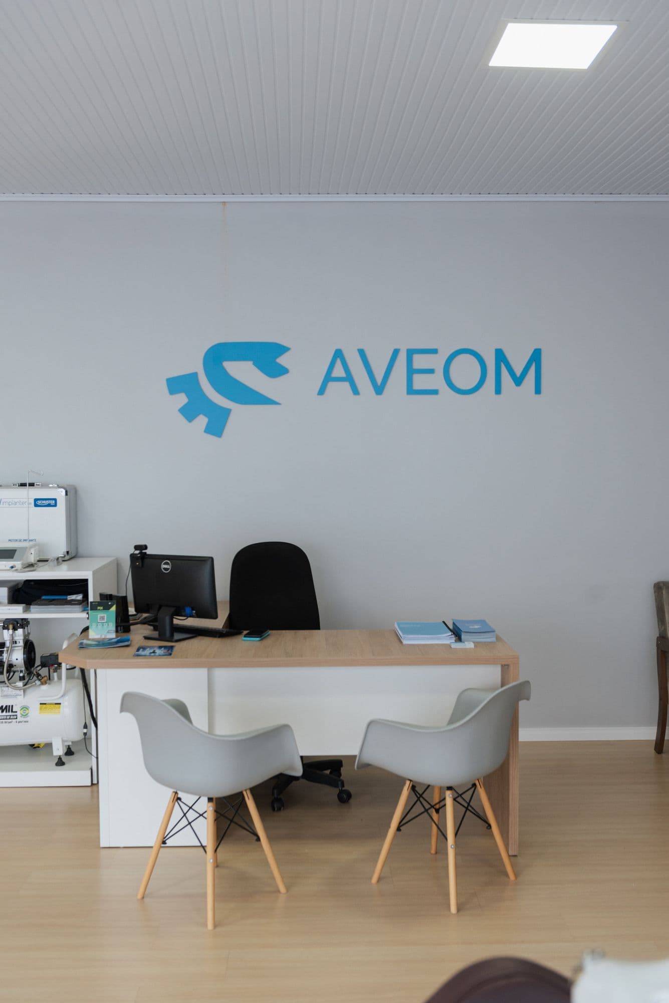 Recepção da Aveom, com o logotipo da empresa na parede